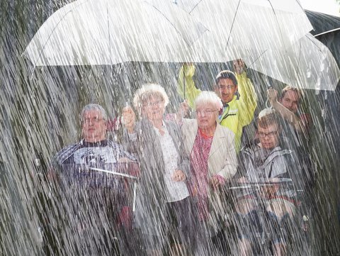 Menschengruppe unter einem Regenschirm