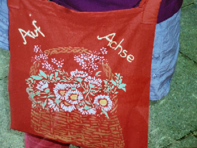Stofftasche mit Blumenkorb-Motiv und den Worten Auf Achse darüber