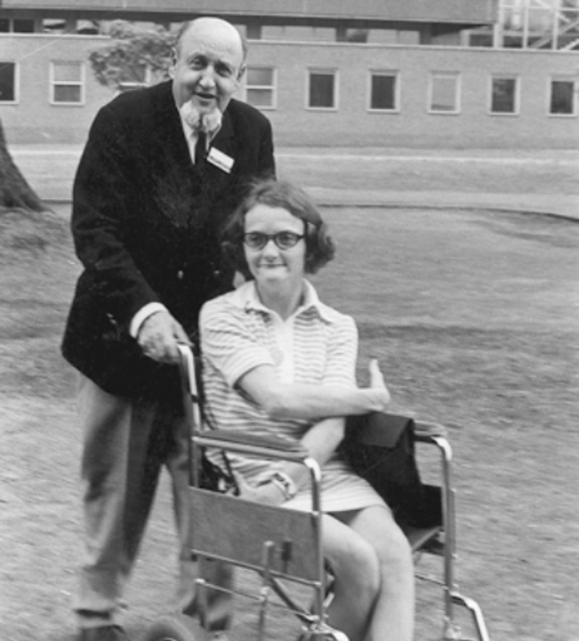 Kurt Juster steht hinter seiner im Rollstuhl sitzenden Tochter Nina