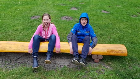 zwei Kinder sitzen auf einem Baumstamm