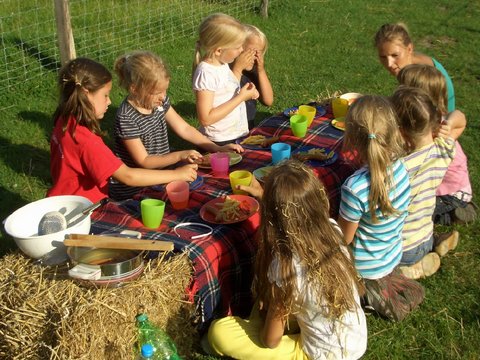 Eine Gruppe Kinder picknickt auf einem Heuballen. 