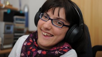 Eine Frau mit Kopfhörern lachend