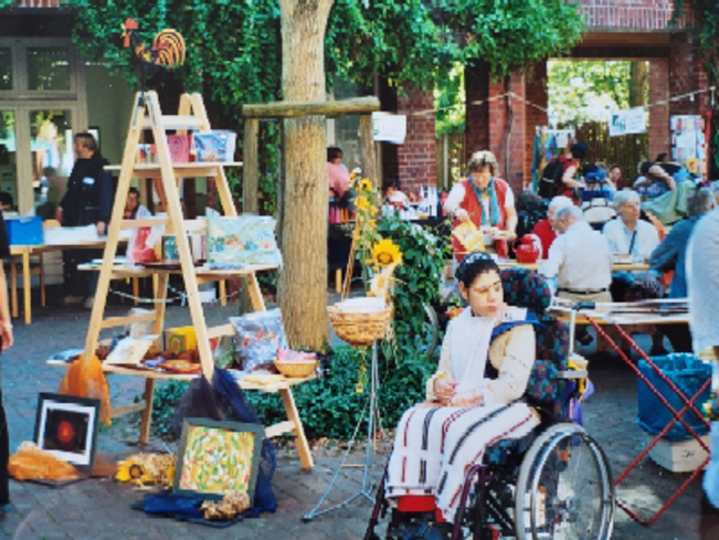 Menschen mit Behinderung und Mitarbeiter*innen zeigen im Innenhof   vom Südring 36 Produkte aus den Tagesstätten, die zum Verkauf angeboten werden.