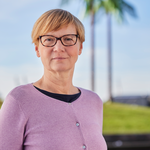 Eine Frau steht vor künstlichen Palmen