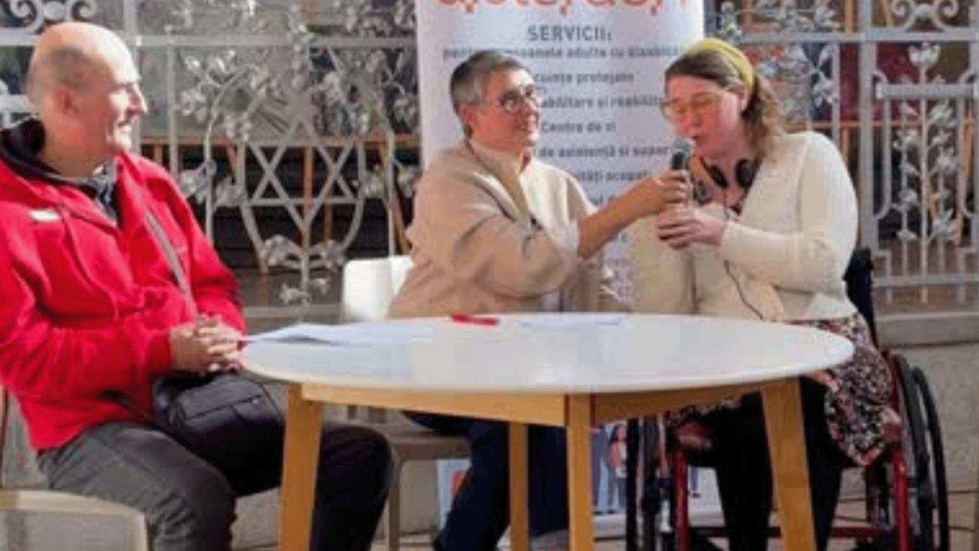 Die Botschafterin der Interessenvertretung von Leben mit Behinderung Hamburg Annika Albers in der Neuen Synagoge in Oradea/Rumänien an einem Tisch mit Anne Becke, links daneben ein Mann