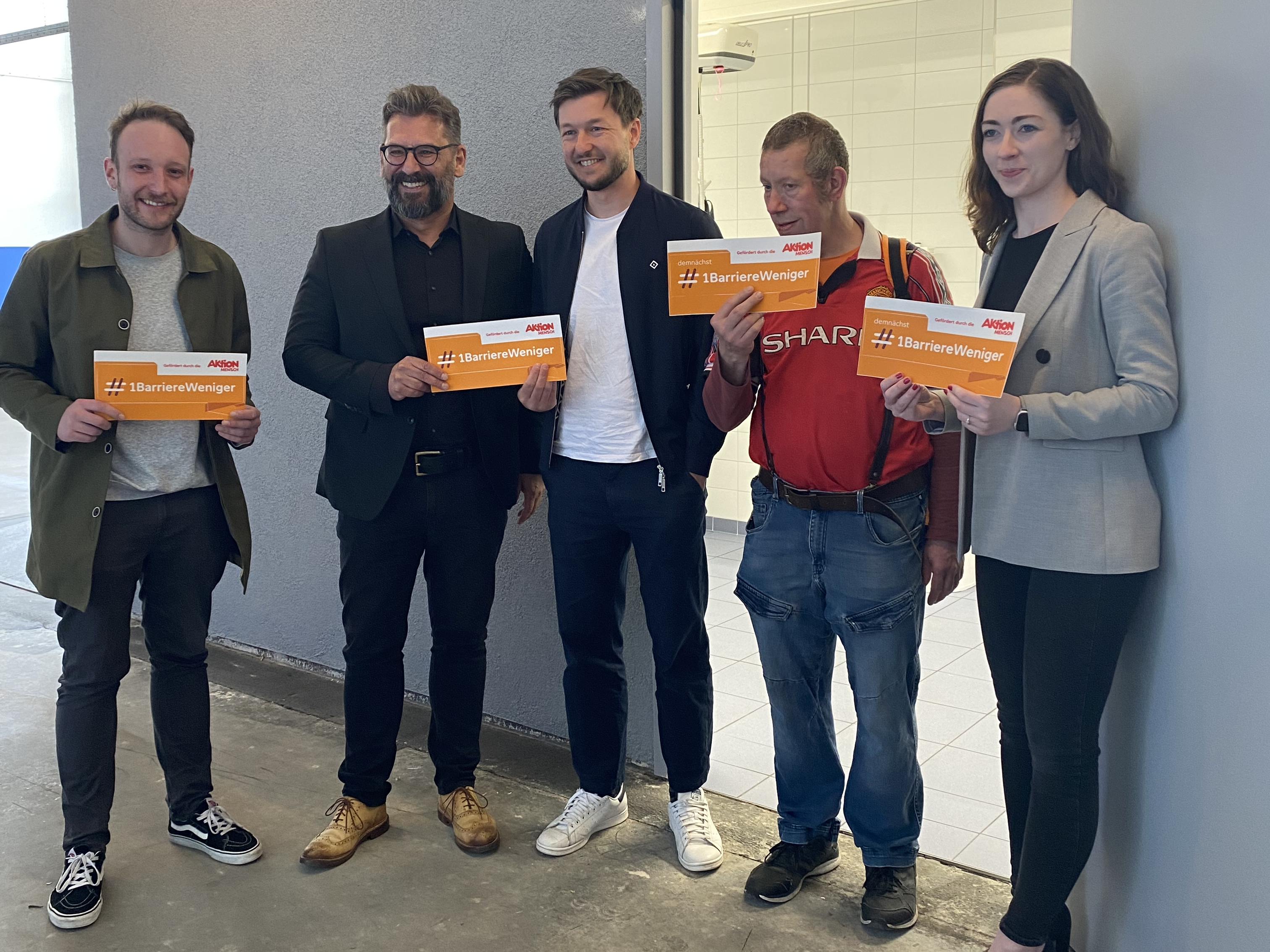 Menschen halten "Gefördert von Aktion Mensch" Schilder in die Höhe.