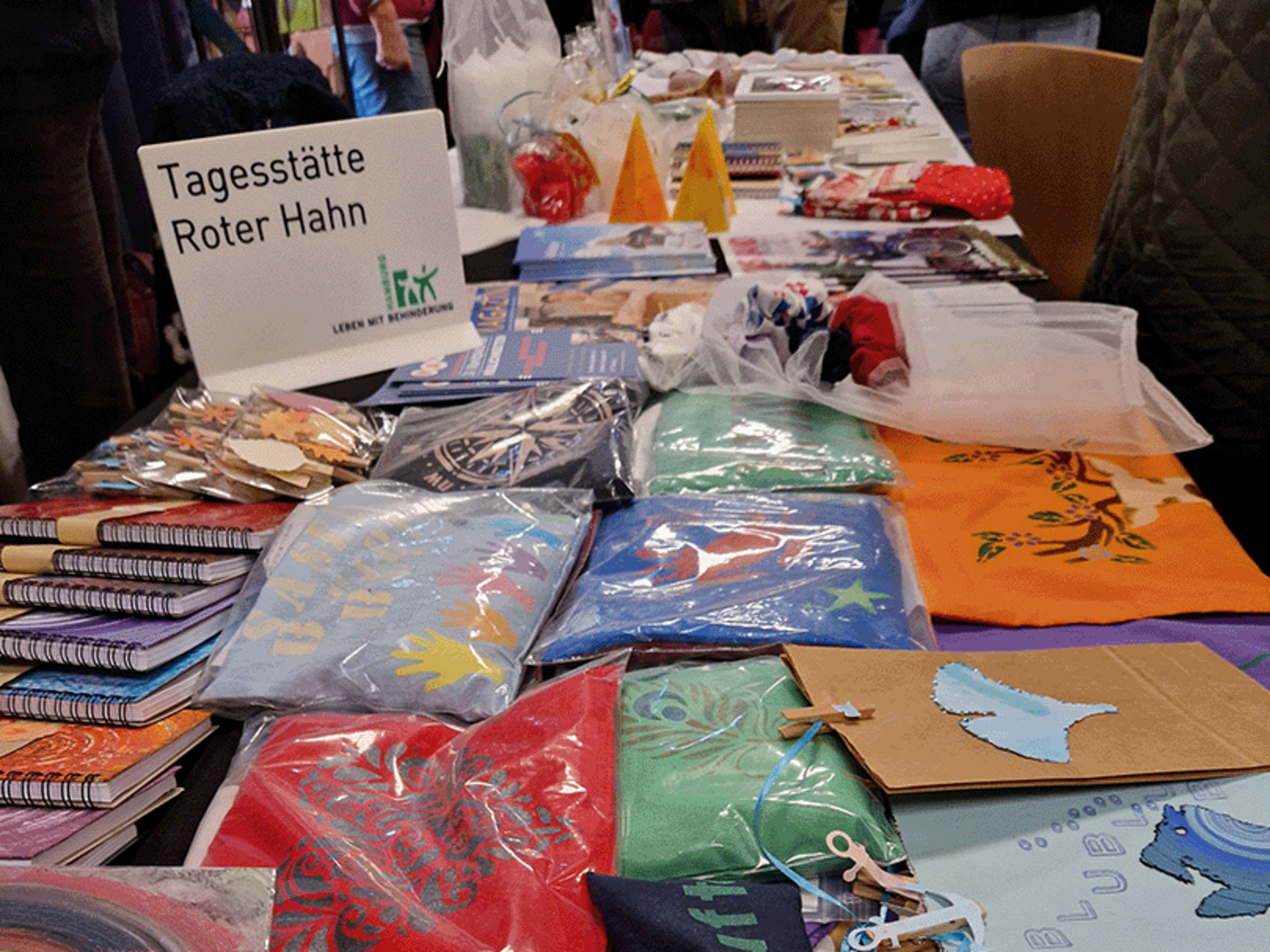NAHT-Markt im Brakula: Stand mit Produkten der Tagesstätte Roter Hahn, unter anderem Kirschkernkissen und Notizbücher.