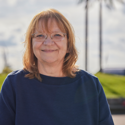 Eine Frau steht vor künstlichen Palmen und lacht.