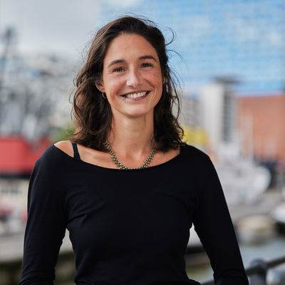 Ein Foto von Jacqueline Maas. Im Hintergrund sieht man die Hamburger Elbphilharmonie