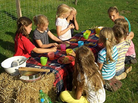 Eine Gruppe Kinder picknickt auf einem Heuballen. 