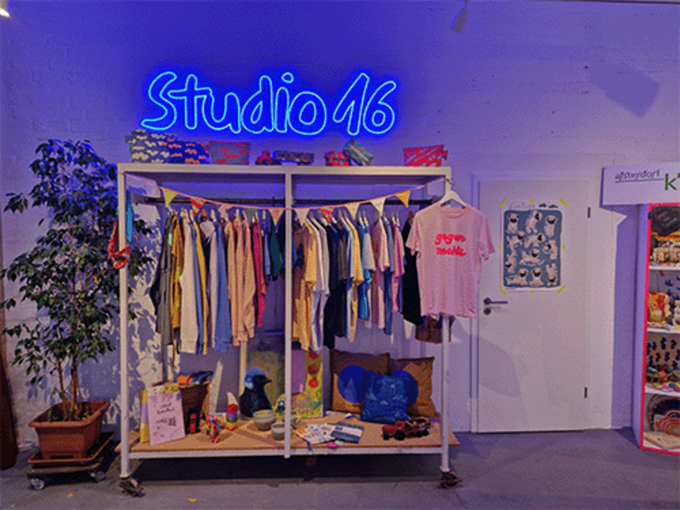ein Kleiderschrank mit Textilien, darüber in Leuchtschrift "Studio 16"