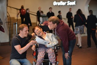 Zwei Kulturbegleiter mit Frau im Rollstuhl im Eingangsbereich der Elbphilharmonie