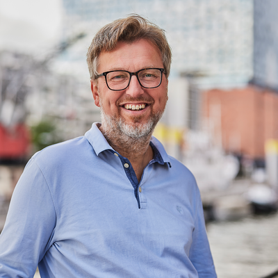 Ein Mann steht vor der Elbphilharmonie und lacht