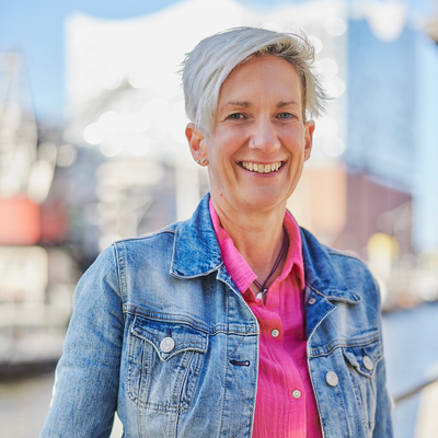 Ein Foto von Bettina Grevel. Im Hintergrund sieht man die Hamburger Elbphilharmonie