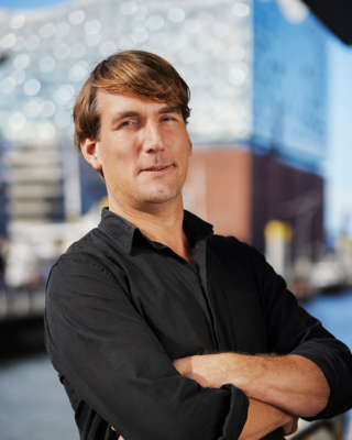 Ein Mann steht mit verschränkten Armen vor der Elbphilharmonie