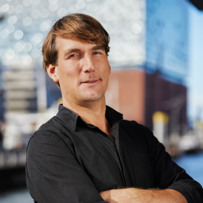 Ein Mann steht mit verschränkten Armen vor der Elbphilharmonie