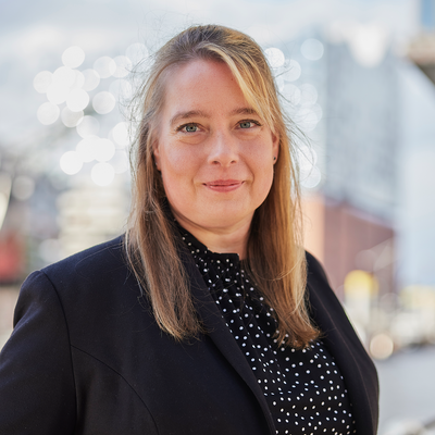 Eine Frau steht vor der Elbphilharmonie und lächelt.