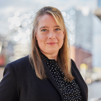 Eine Frau steht vor der Elbphilharmonie und lächelt.