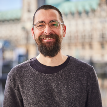 Ein Foto von Christian Oppermann. Im Hintergrund sieht man das Hamburger Rathaus