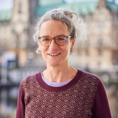 Ein Foto von Andrea Voss. Im Hintergrund sieht man das Hamburger Rathaus