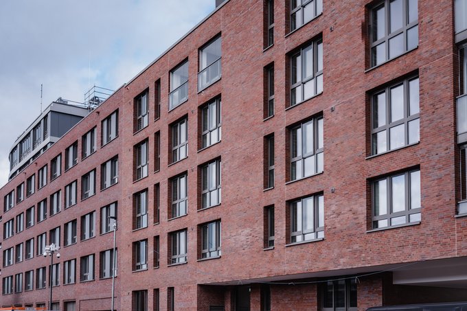Mehrgeschossiges Bauwerk mit roter Backsteinfassade an urbaner Straße.