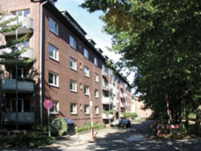 Straße mit mehrstöckigen Wohngebäuden aus Backstein und Bäumen am Straßenrand
