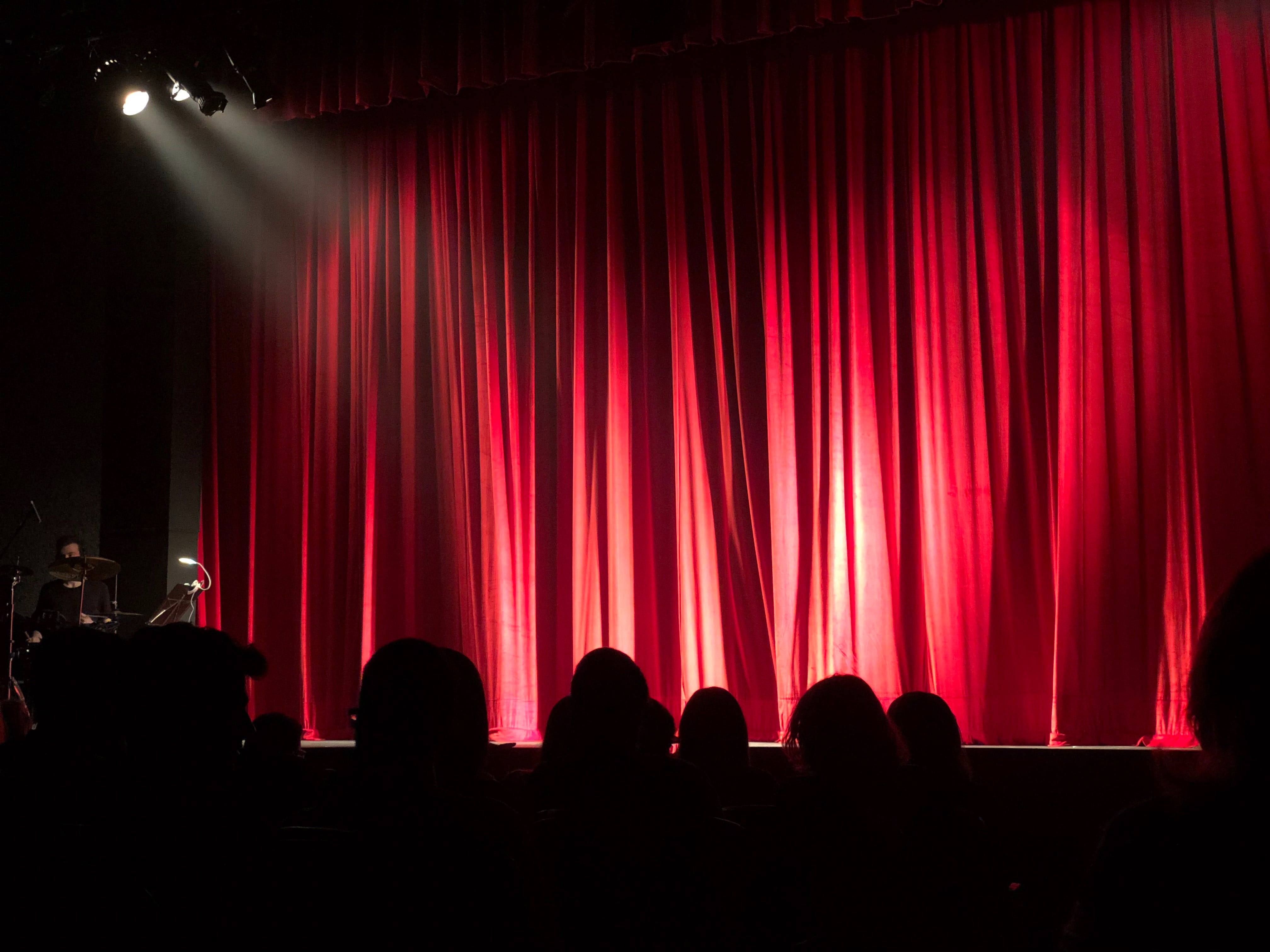 Theaterbühne mit geschlossenem Vorhang und Publikum im Vordergrund