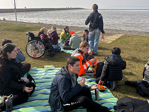Titelbild Ferienreisen 2027: Junge Menschen an der Meeresküste