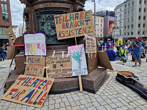 Titelbild Kundgebung am Gänsemarkt Hamburg. Protestschilder am Lessingdenkmal, im Hintergrund Demonstranten